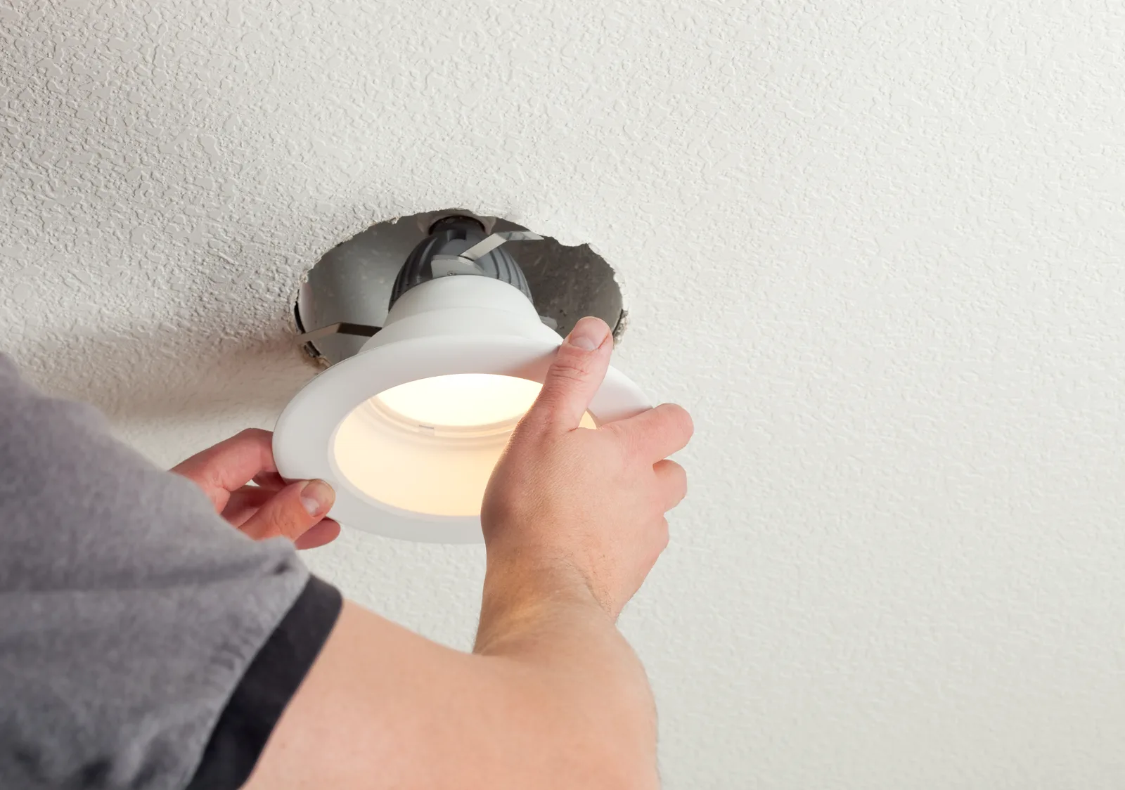 Electrician fitting a ceiling light for a local homeowner